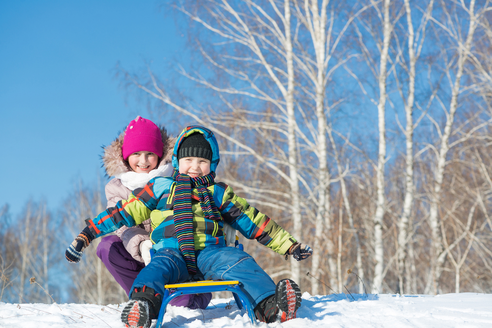 Two cute kids riding a sled and having fun